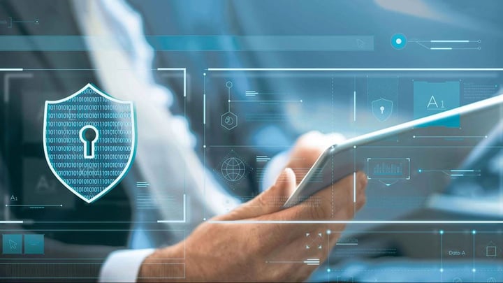 Primo piano di una mano che aziona un tablet con interfacce di sicurezza digitali: un cartello blu con codice binario fluttua sopra lo schermo, circondato da ologrammi come un globo e flussi di dati, simbolo del voto elettronico sicuro presso la Posta Svizzera.