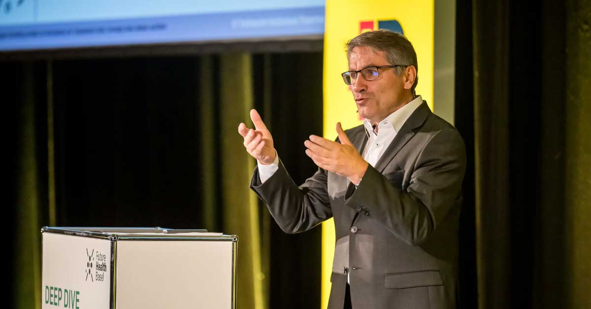 Prof. Dr. Franz Benstetter spricht auf einer Bühne und gestikuliert vor einem Rednerpult mit der Aufschrift „Deep Dive“. Im Hintergrund sind ein gelbes Banner und eine Leinwand sichtbar. Prof. Dr. Franz Benstetter spricht auf einer Bühne und gestikuliert vor einem Rednerpult mit der Aufschrift „Deep Dive“. Im Hintergrund sind ein gelbes Banner und eine Leinwand sichtbar.