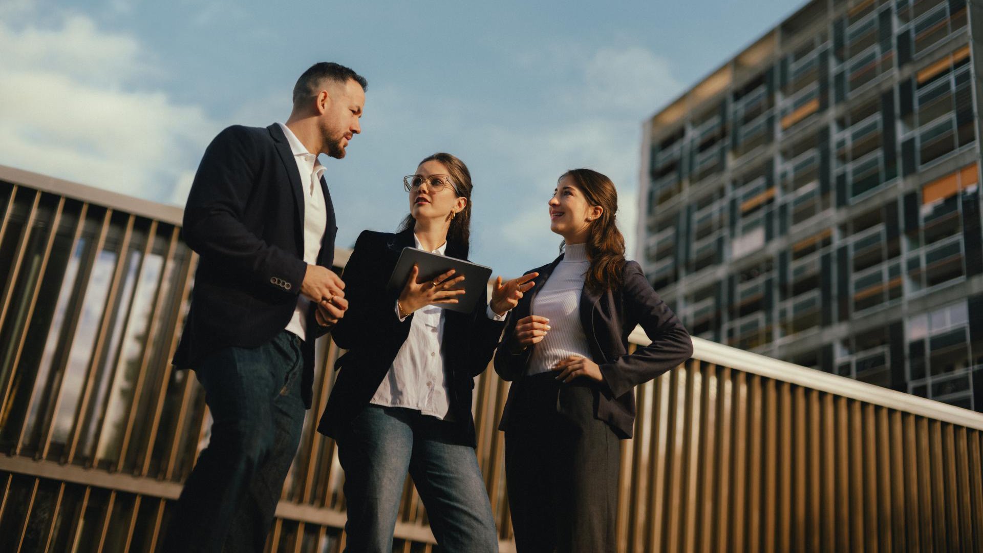Un homme et deux femmes discutent dehors devant des immeubles de bureaux. Un homme et deux femmes discutent dehors devant des immeubles de bureaux.
